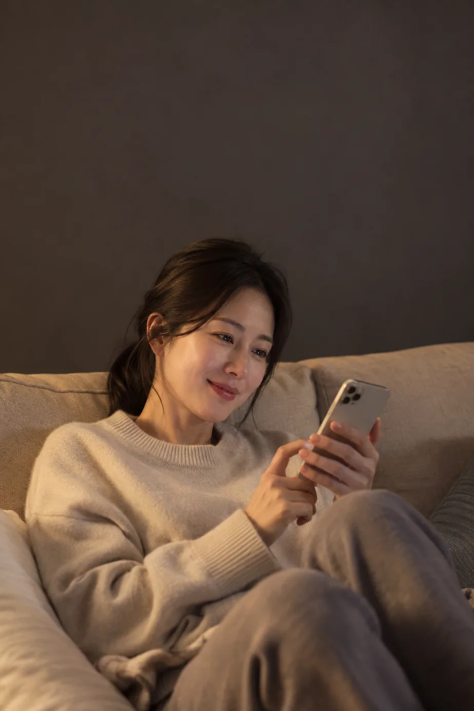 저녁에 소파에서 스마트폰을 보는 여성